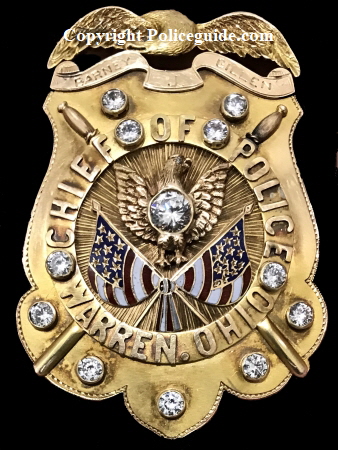 Stunning 10k gold eagle topped shield, surmounted with a Phoenix rising above two American flags.  Twelve brilliant diamonds adorn the shield which is completed with crossed police batons. Marked "Barney J. Gillen, Chief of Police, Warren, Ohio".