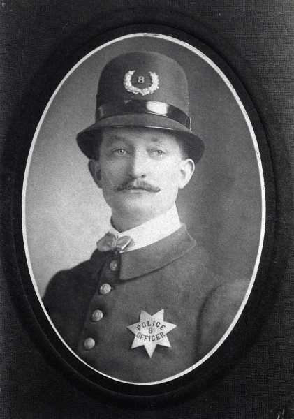 Photo of a young John N. Black wearing San Jose Police badge No. 8 pie plate.