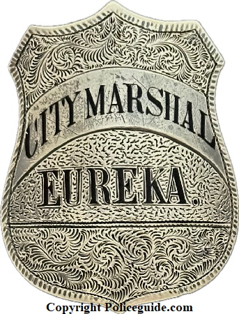 City Marshal Eureka shield, sterling silver, hand engraved, hard fired black enamel lettering.  The first City Marshal for Eureka was appointed in 1858.  On June 9, 1887 Ordinance 110 specifically designated the City Marshal as the ex-officio police chief.  In 1895 the title “City Marshal” was eliminated and the position of “Chief of Police” was created.