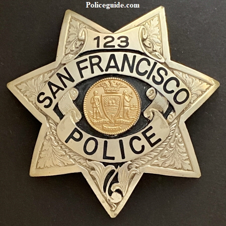 S.F.P.D. Prototype Badges.  Back in the 1970’s it was felt by the department that they should explore going to a more unique police badge.  Irvine & Jachens was tasked with coming up with new designs for consideration.  These three prototype’s were considered.  Badge number 88 was the badge number assigned to officer Russ Dickey.   Russ was issued the badge to wear on duty and seek opinions and feedback from fellow officers and the public.  Both badges 88 and 123 are sterling silver with hand engraved leafing highlighted by recessed black enamel.  Badge 0000 was a departure from the 7 point star worn for more than 100 years.  The badge featured reverse blue enameled panels and borders and a sterling silver city seal.  Tradition won out and it was decided no change would be made.  To this day badge 88 worn by Russ Dickey is the only department authorized prototype badge to be worn.