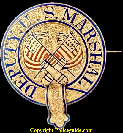 Post Civil War jeweler made Deputy U. S. Marshal badge made in the classic police belt design.  14k gold layered over a sterling silver base.  Red and blue hard fired enamel highlight the crossed U.S. flags and the crossed cannons.  