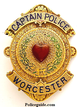Worcester Captain badge made of 14k gold with a red heart in the center surrounded by a green enameled wreath.  Badge is completely hand engraved with enameled lettering in Royal Blue, circa 1888.